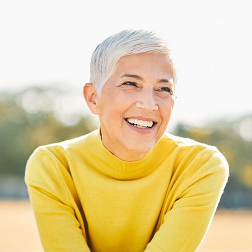 Senior woman sitting outside smiling