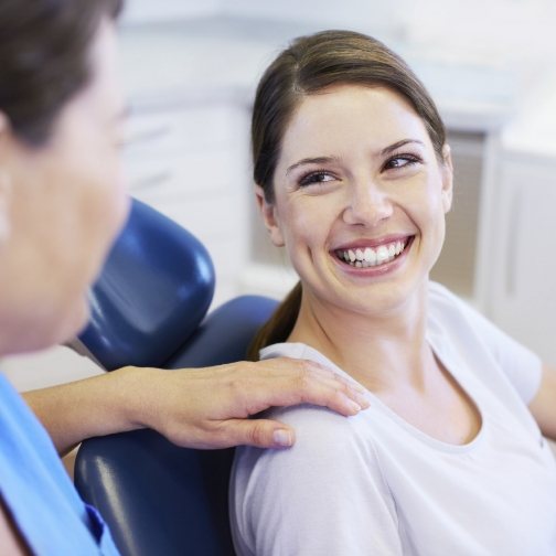 Young woman in dental chair grinning at her dentist