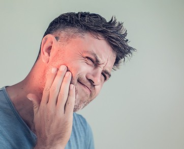 a man holding his jaw in discomfort
