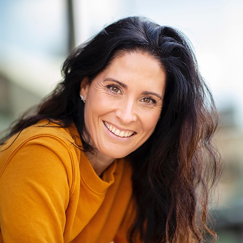 Woman in orange shirt leaning forward and smiling