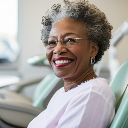 Senior woman smiling in dental chair with a CEREC same day dental crown