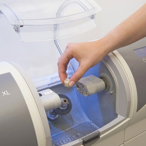 Dentist placing small ceramic block into CEREC machine