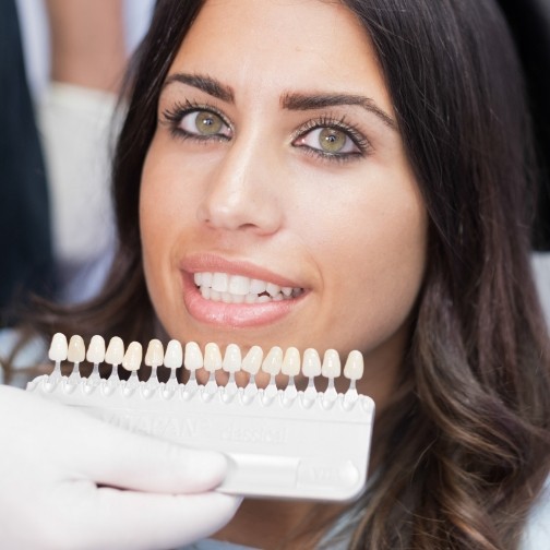 Fort Worth cosmetic dentist holding a shade guide next to a smiling patient