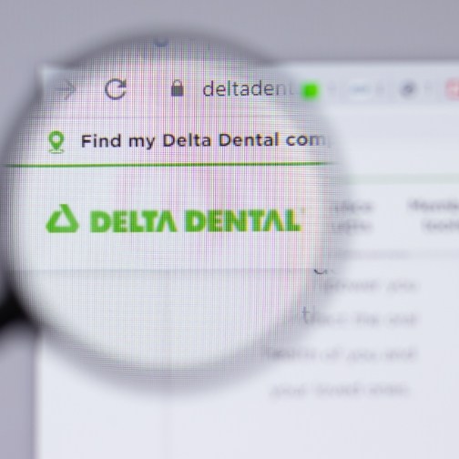 Magnifying glass on computer screen showing logo for Delta Dental insurance on their website