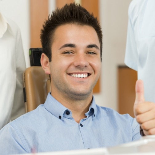 Smiling man giving thumbs up in dental chair
