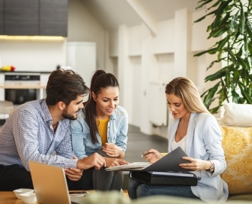 Man and two women sitting at table looking at paperwork