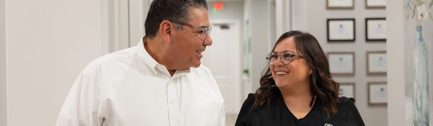 Man smiling at dental team member in hallway after dental services in Fort Worth