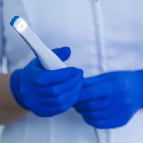 Dental professional holding a thin white intraoral camera