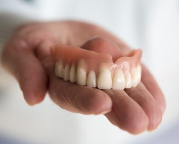 Hand holding a full upper denture