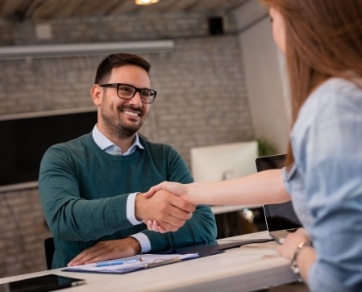 Man shaking hands with dental team member across desk