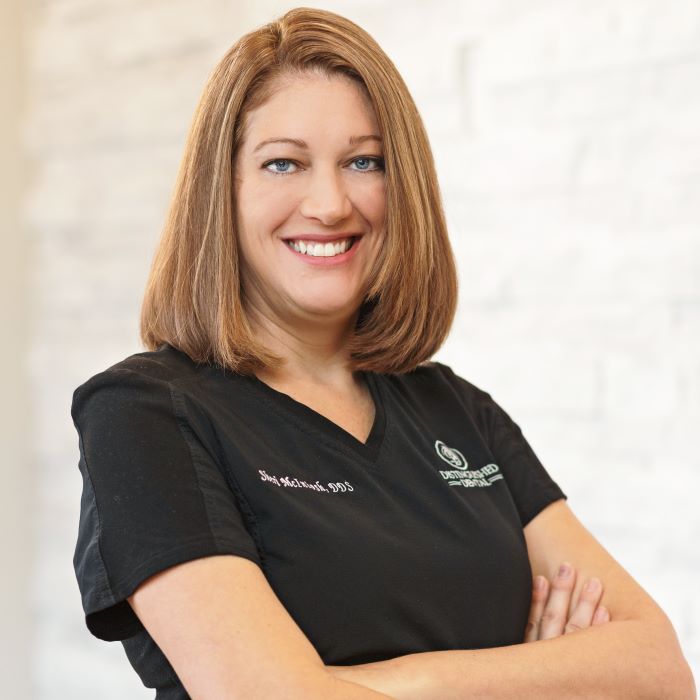 Fort Worth dentist Doctor Sheri McIntosh smiling with her arms crossed