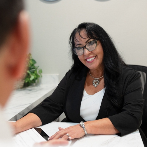 Dental team member at desk smiling at patient