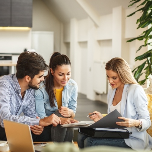 Man and two women sitting at desk and looking at paperwork