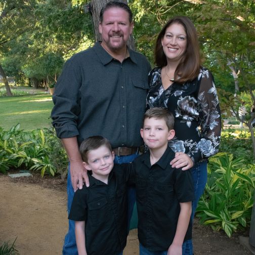 Doctor McIntosh smiling in forest with her husband and two sons