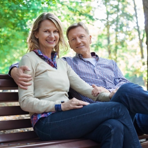 Smiling older man and woman sitting on park bench together