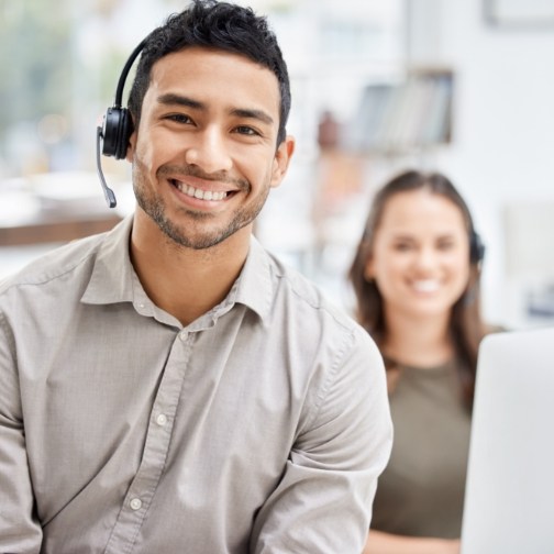 Smiling man sitting in office desk and wearing headset