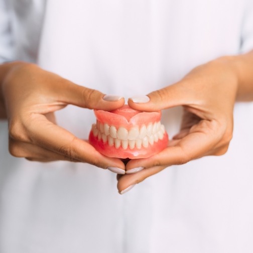 Dentist holding a set of full dentures for replacing missing teeth