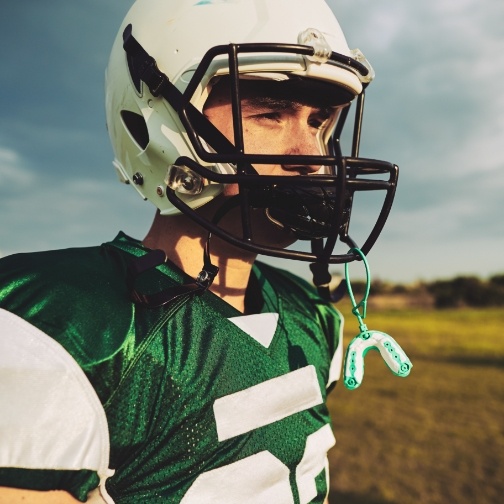 Football player with mouthguard hanging from their helmet