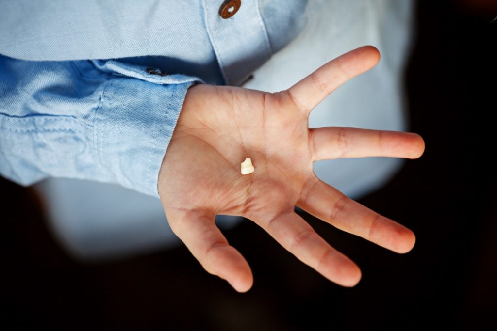 Someone holding a knocked out tooth before seeing an emergency dentist