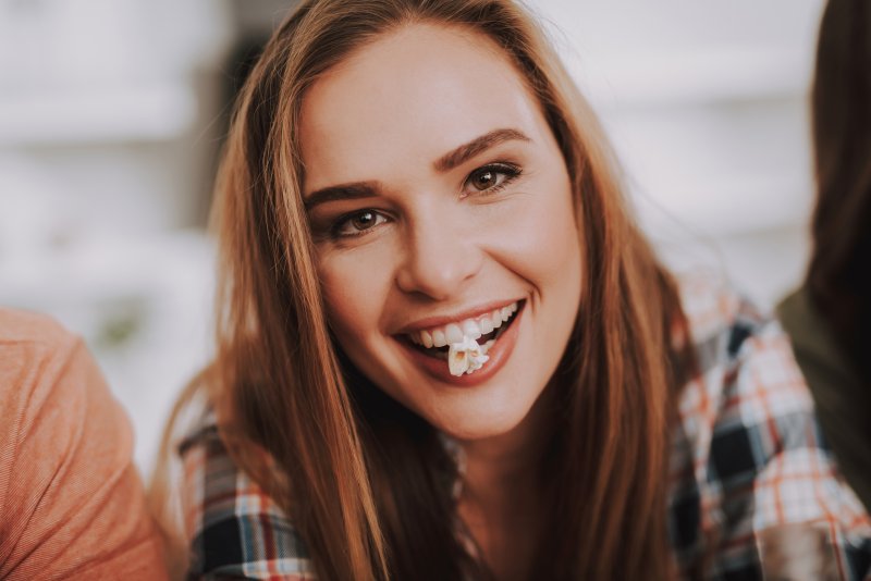 A woman eating popcorn, one of the foods that can chip teeth