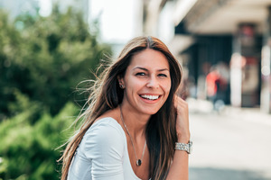 Woman with brown hair sitting outside and smiling 
