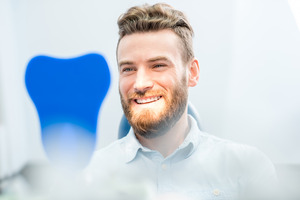 Male dental patient checking smile in mirror