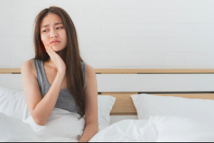 Woman sitting up in bed with a toothache